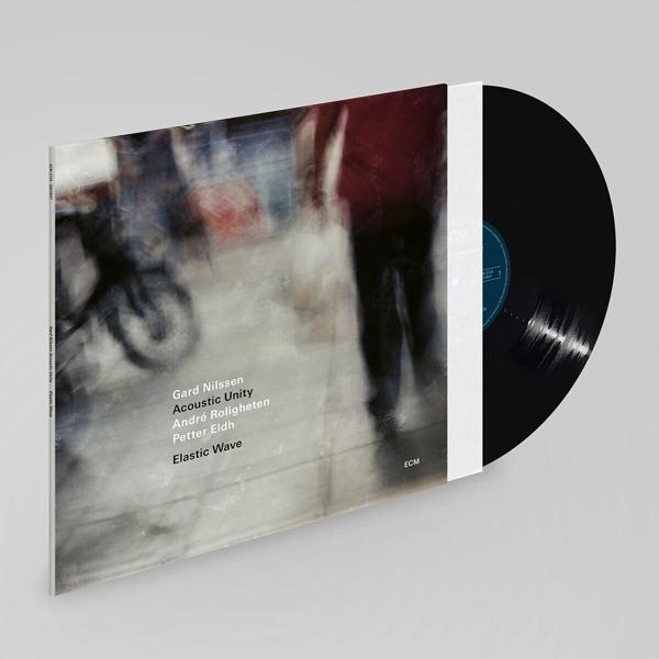 Egy bakelit lemezalbum, homályos alakokat ábrázoló borítóval. Az album fehér borítóban van. A lemez fekete.