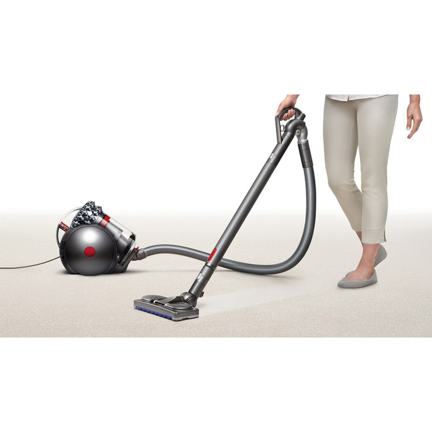 Una persona che utilizza un aspirapolvere Dyson su un pavimento in moquette.