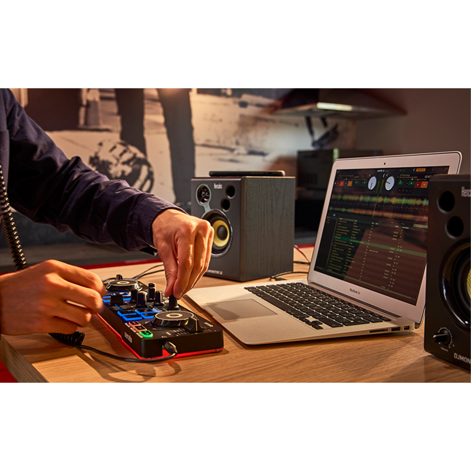Console di missaggio DJ con laptop e diffusori su tavolo legno.