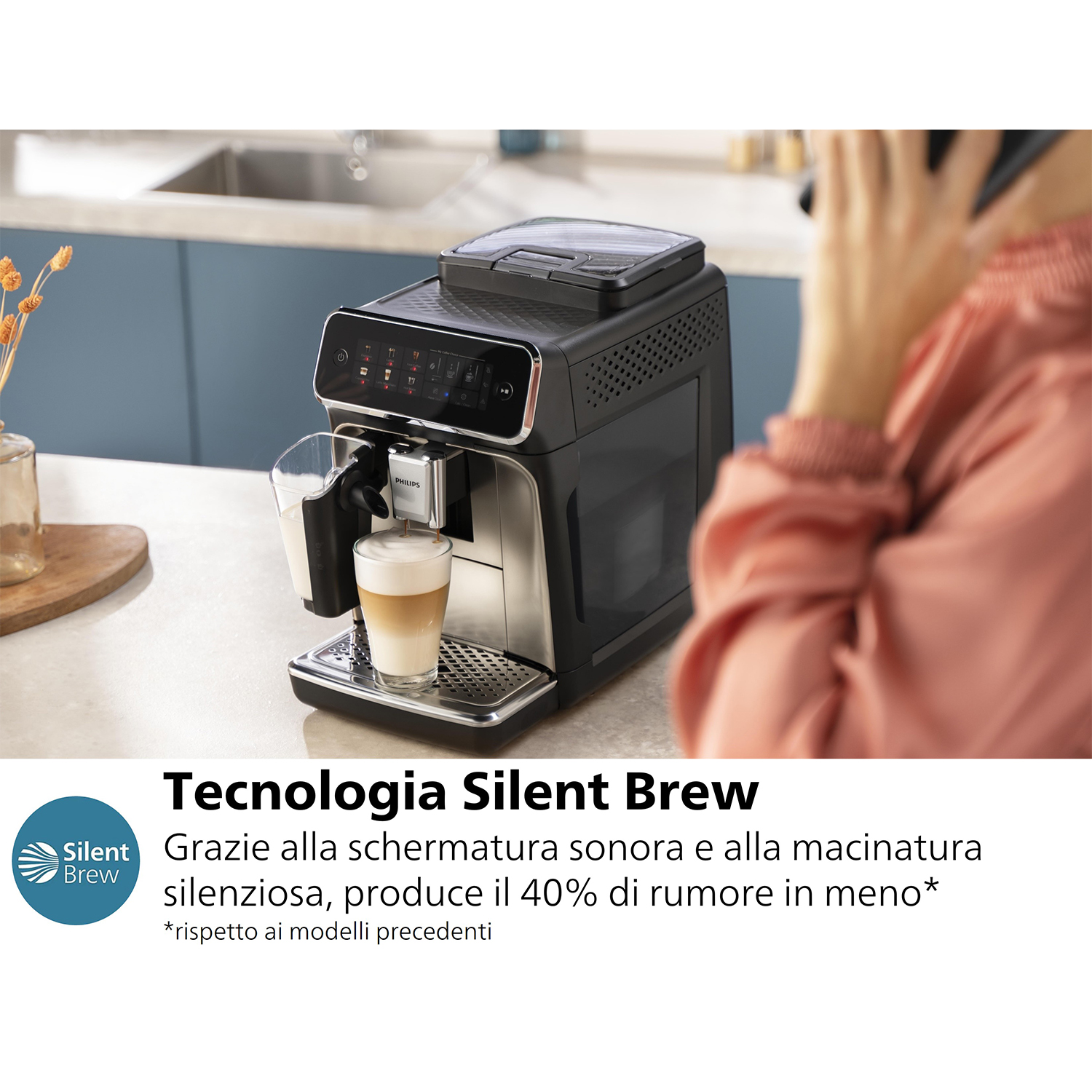 Una macchina da caffè nera e argento con un bicchiere di latte macchiato in cucina.