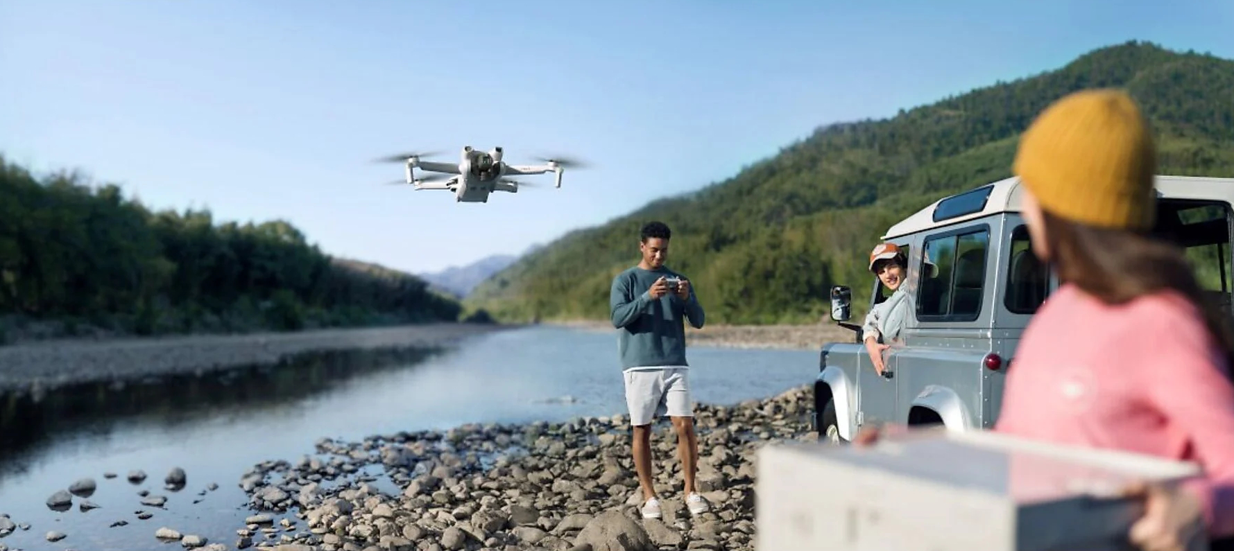 Dron latający nad rzeką. Ludzie są w pobliżu samochodu na brzegu rzeki.