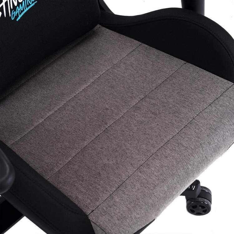 Primer plano del asiento de una silla gaming gris y negro. Tiene costuras verticales y laterales negros.