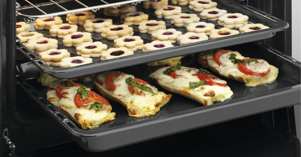 Sütő két tálcával: a felsőn sütemények, az alsón pizzához hasonló kenyér.