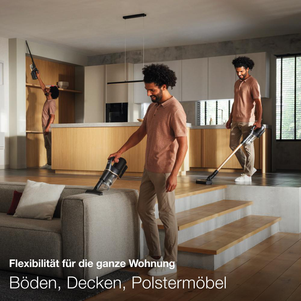 Mann saugt Sofa. Zwei weitere Männer im Hintergrund machen das Gleiche.