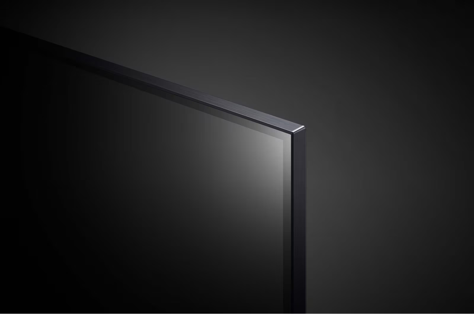 Zbliżenie rogu czarnego ekranu telewizora z cienką srebrną ramką na ciemnym tle.