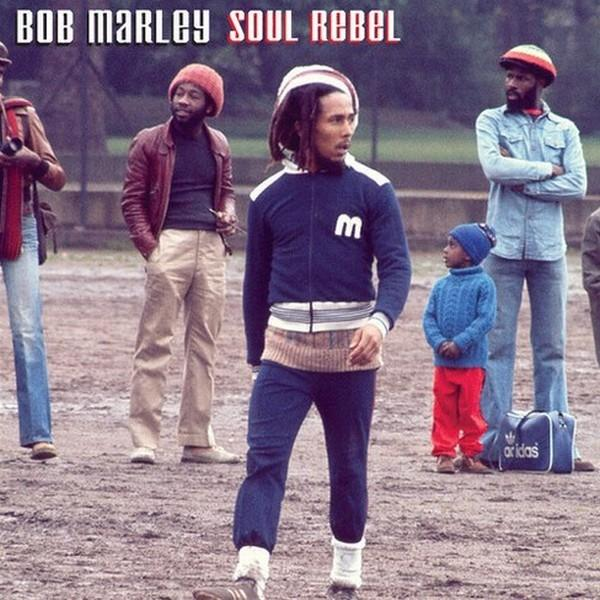 Bob Marley a zenekar tagjaival. Marley kék melegítőt visel. Mások hétköznapi ruhát viselnek. A háttér füves. Cím: Bob Marley Soul Rebel.