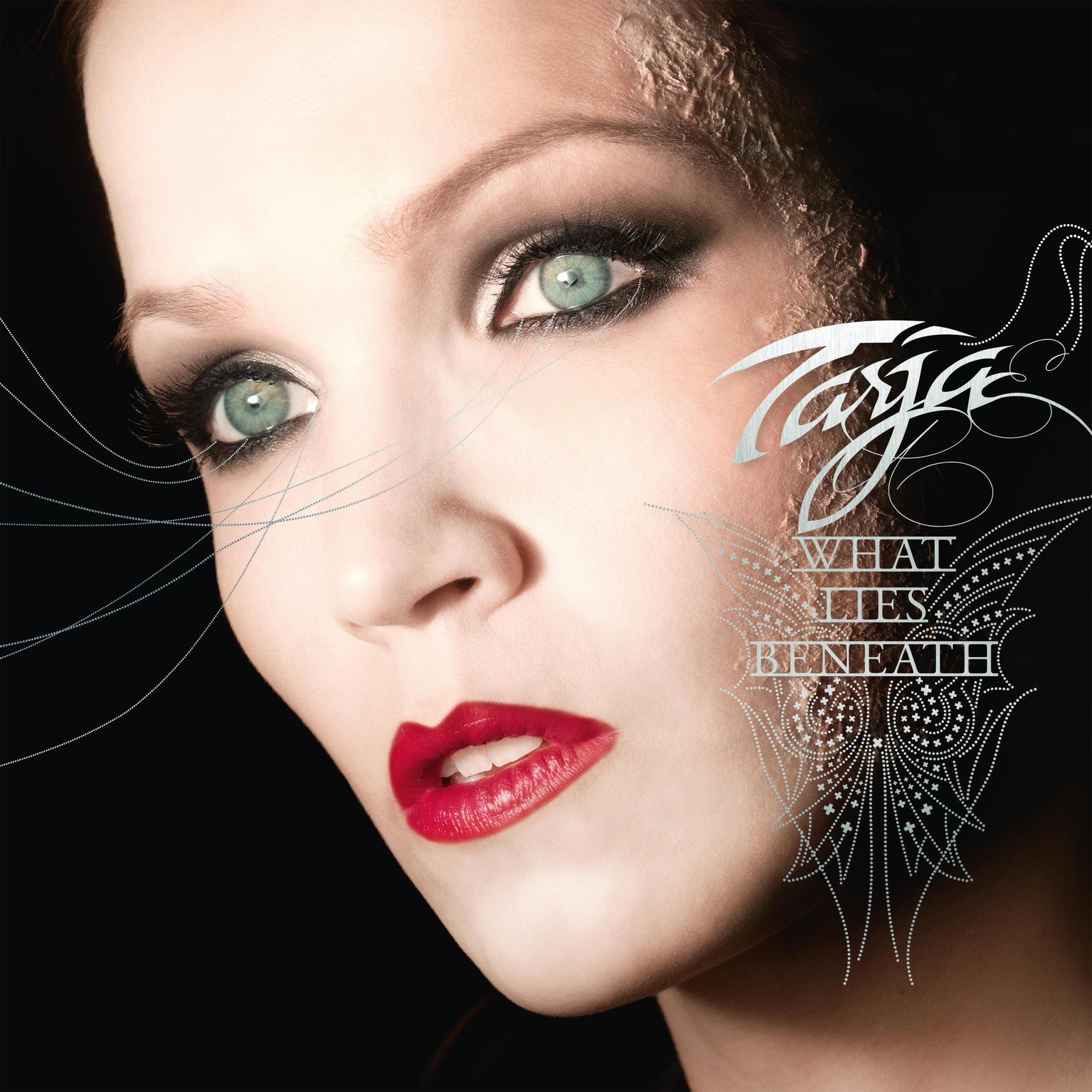 Egy nő közelképe sötét szemsminkkel és piros rúzzsal. A szöveg azt mondja: „Tarja What Lies Beneath”.