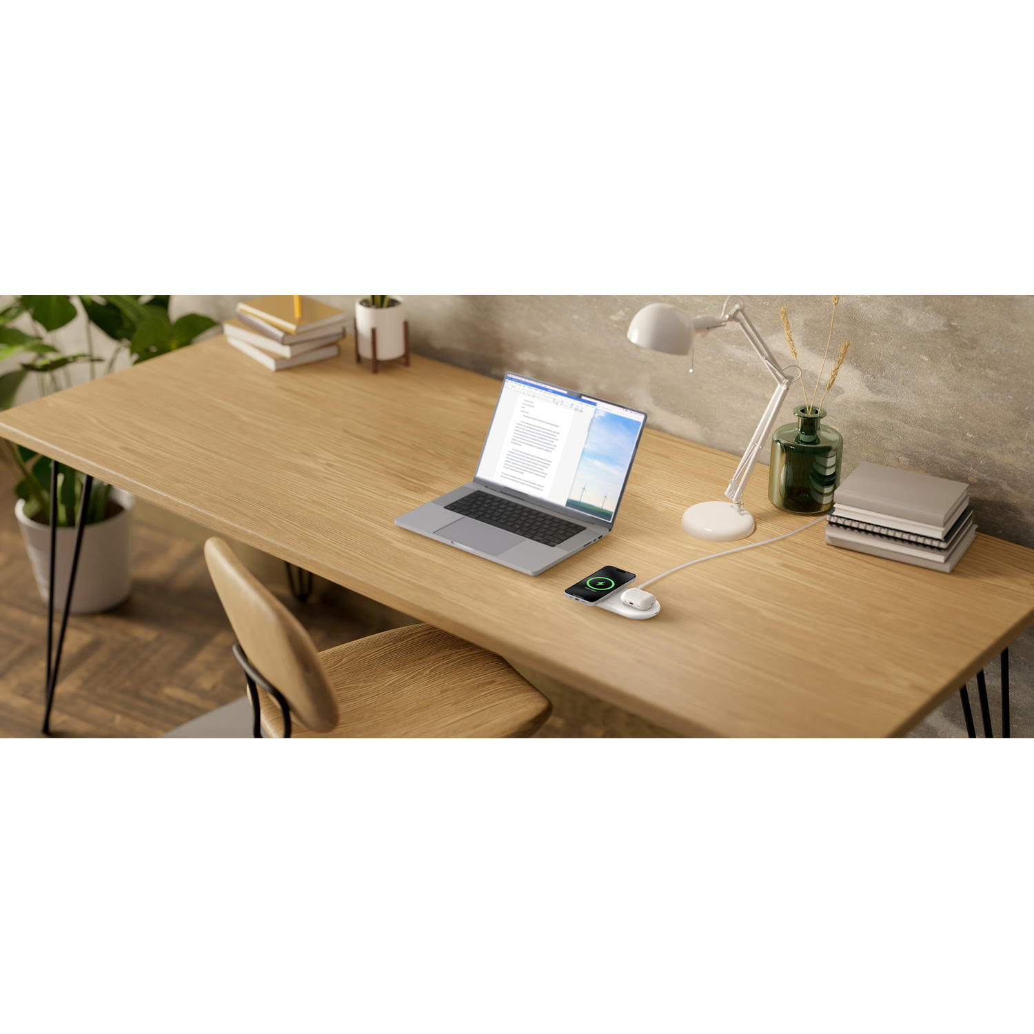 A desk with a laptop, wireless charger, lamp, and books.