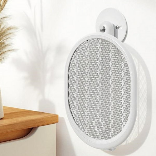 Biała elektryczna packa na komary na białej ścianie. Packa jest owalna i ma wzór siatki.