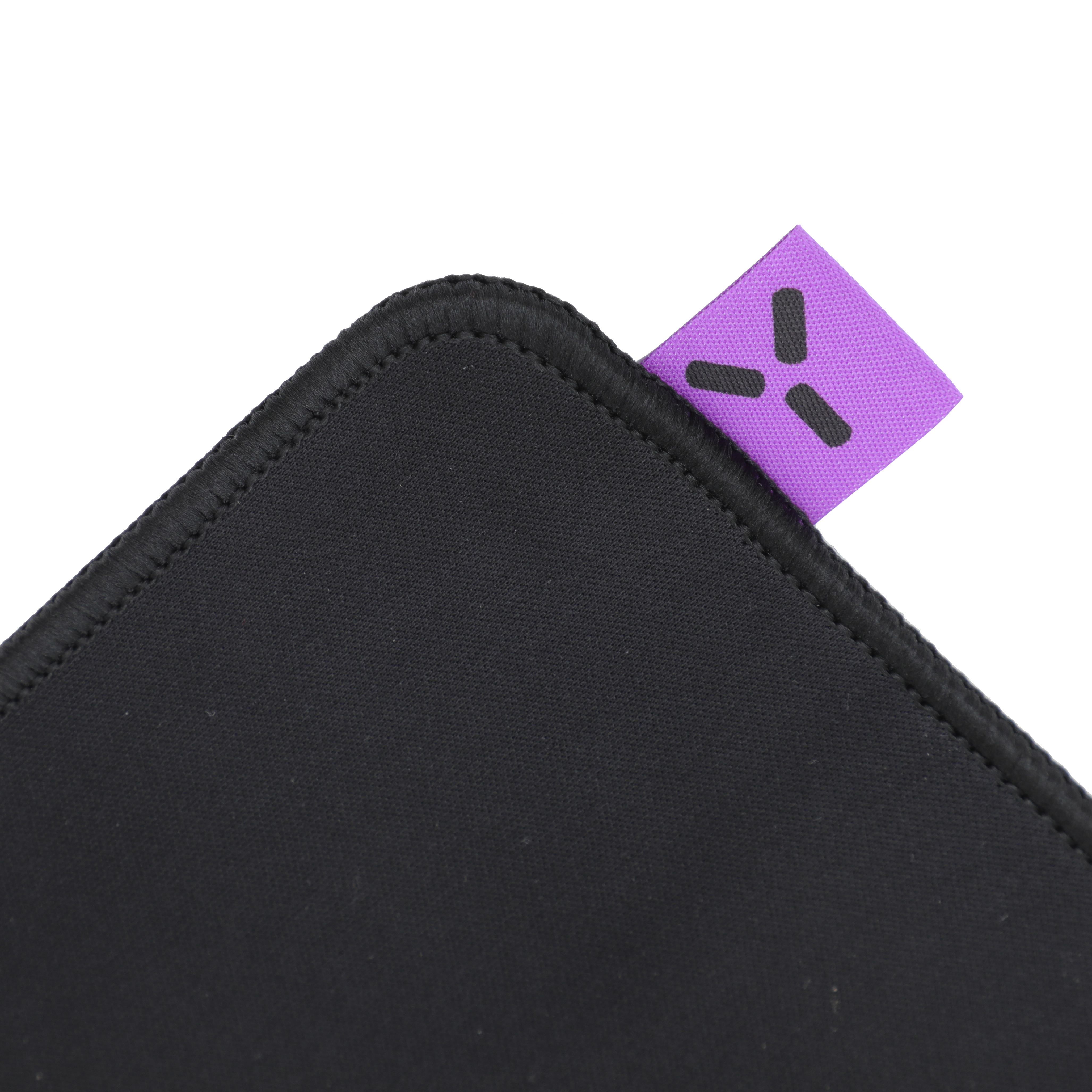 Nahaufnahme eines schwarzen Mauspads mit einem lila Etikett und schwarzem Logo auf weißem Hintergrund. Das Pad hat genähte Kanten.