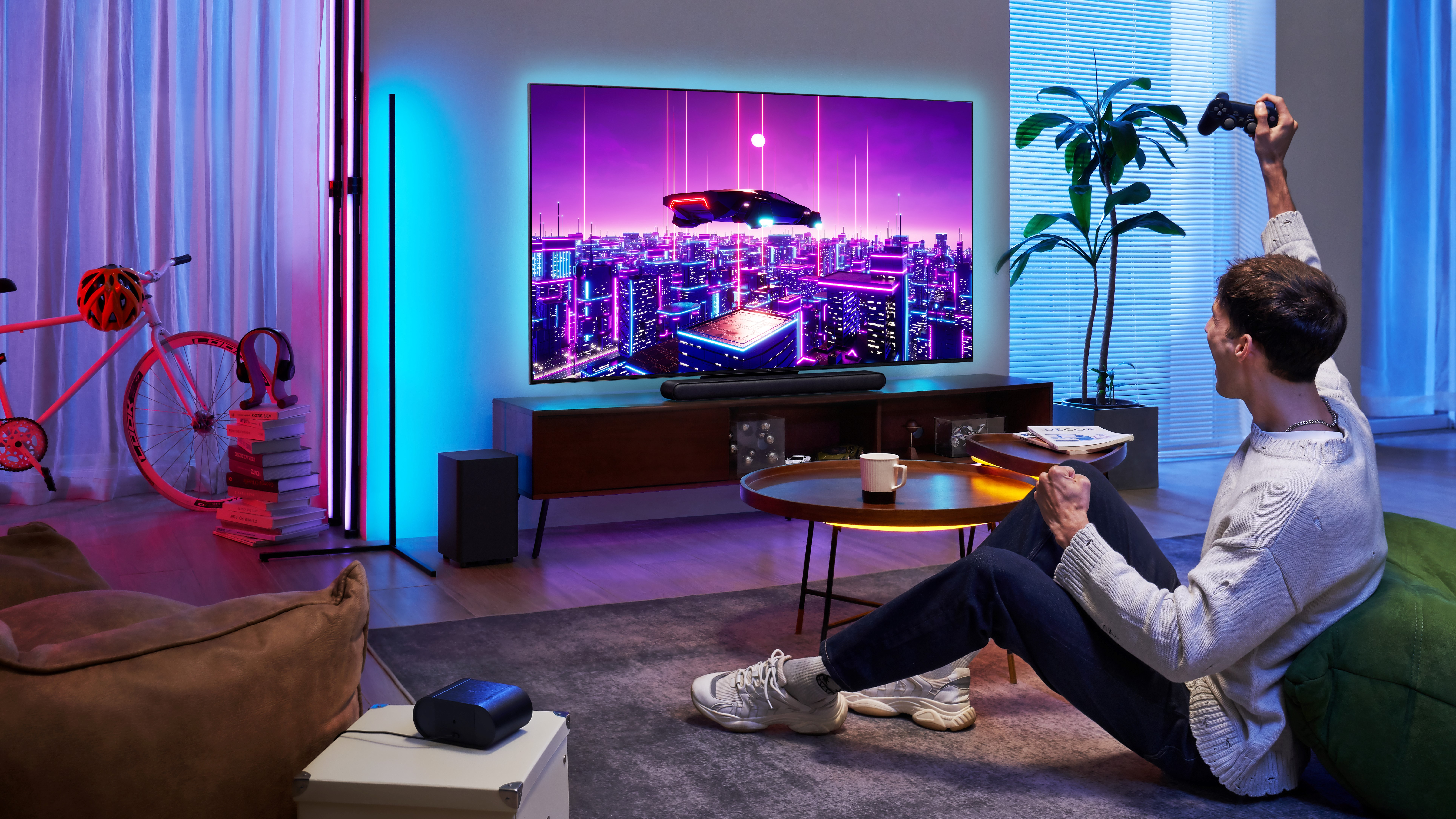 Mann spielt Spiel auf großem Fernseher mit bunten Lichtern; eine Raumszene.