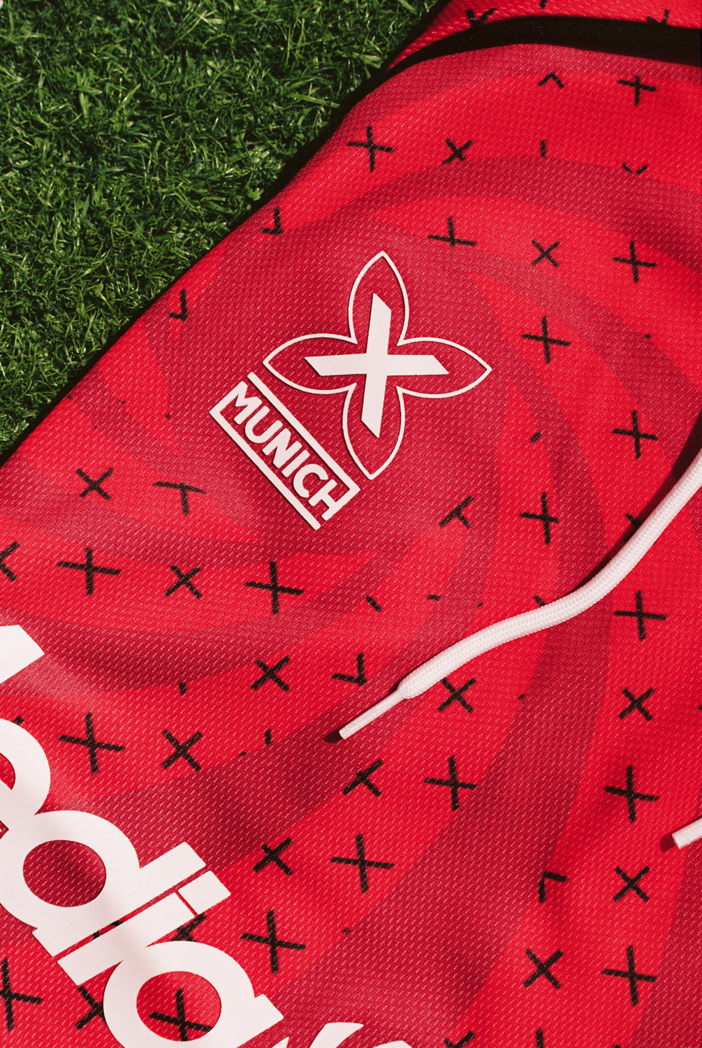 Pantalones cortos deportivos Munich en rojo con patrón de cruces negras y el logo de la marca en blanco.