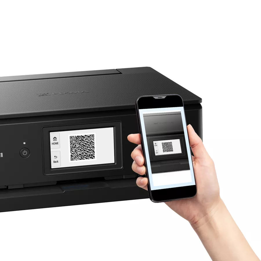 Una impresora negra con una pantalla que muestra un código QR. Una mano sostiene un teléfono con el mismo código QR.