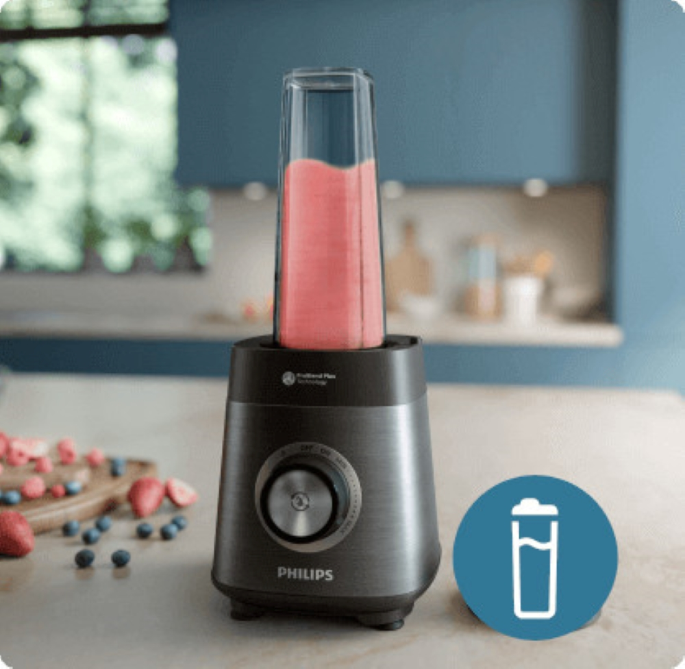 Blender z różowym smoothie. Czarna i srebrna podstawa. Tło kuchenne z owocami. Niebieska ściana akcentowa.