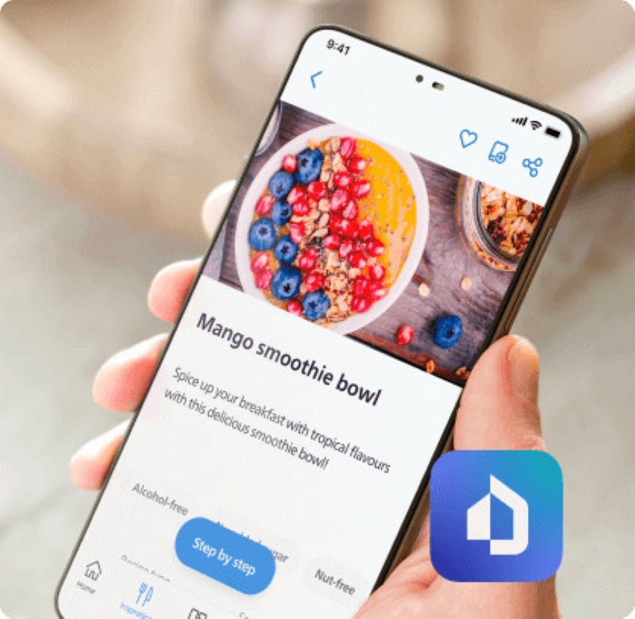 Ręka trzymająca telefon z przepisem na smoothie mango, z ikoną domu.