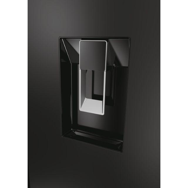 Eine schwarze Kühlschranktür mit eingelassenem Griff und einem silbernen Spender vor dunklem Hintergrund.
