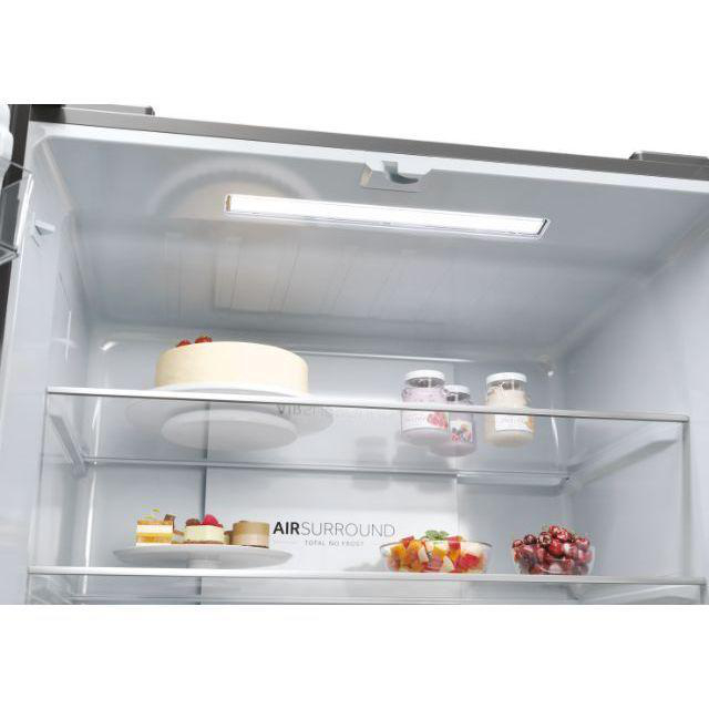 Innenraum eines Kühlschranks mit Lebensmitteln auf den Regalen, darunter ein Kuchen und Obst.