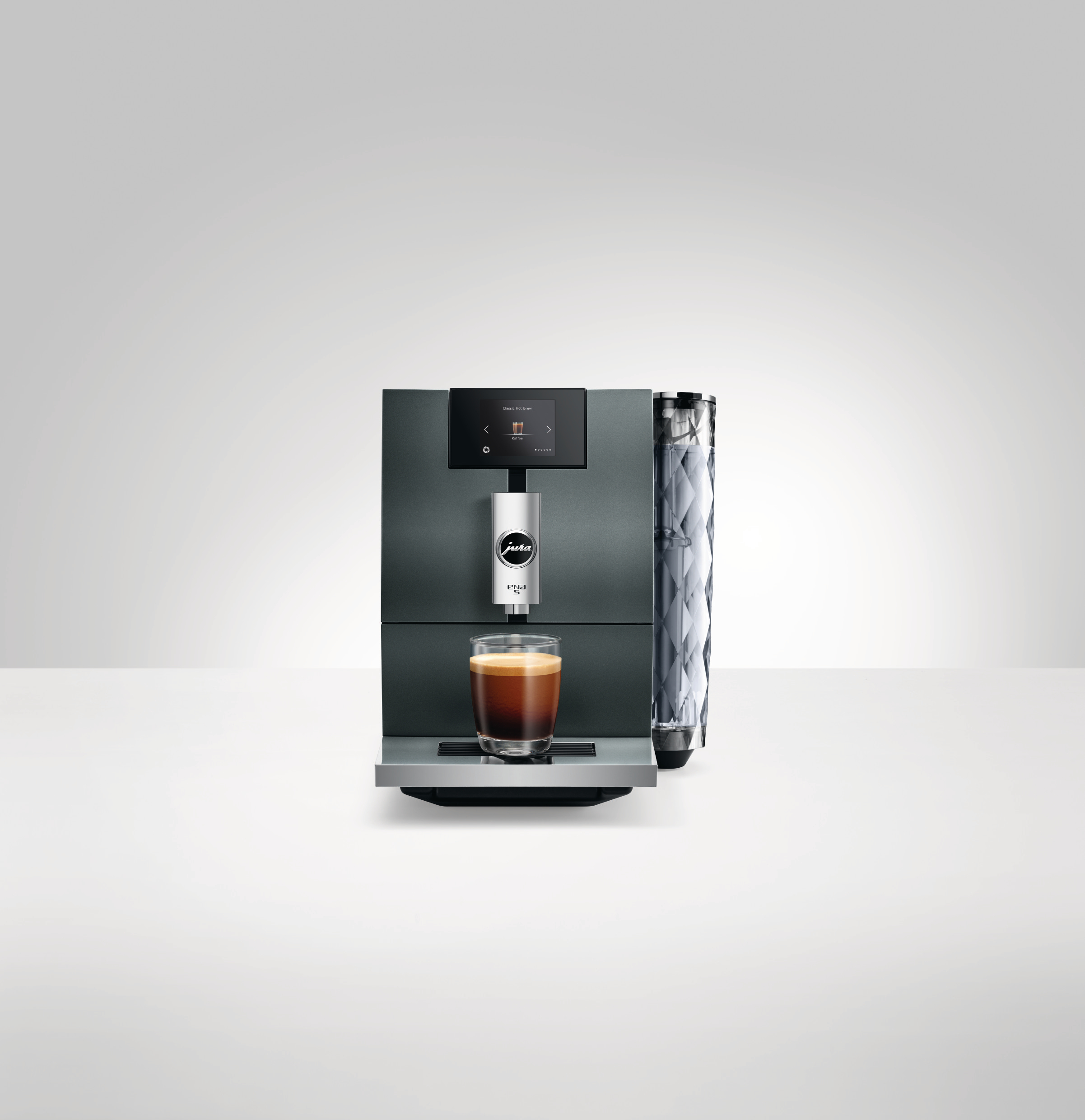 Jura ENA 8 Kaffeemaschine mit einem Glas Espresso, Vorderansicht, vor weißem Hintergrund.