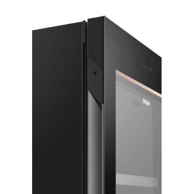 Schwarze Kühlschranktür mit dunkler Glasplatte und dem Haier-Markenlogo.