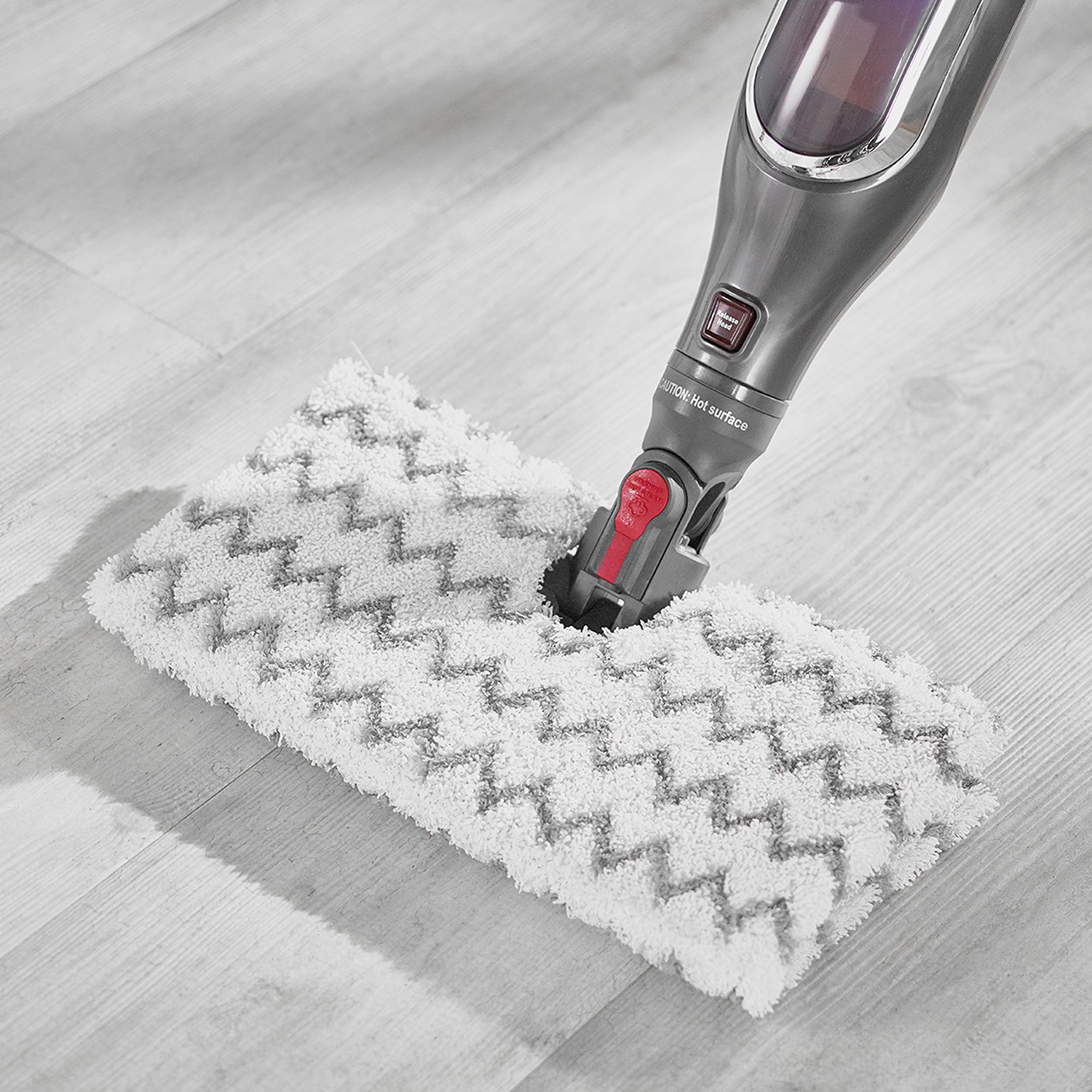 Una scopa a vapore su un pavimento in legno, che pulisce con un tampone a zig-zag bianco e grigio.