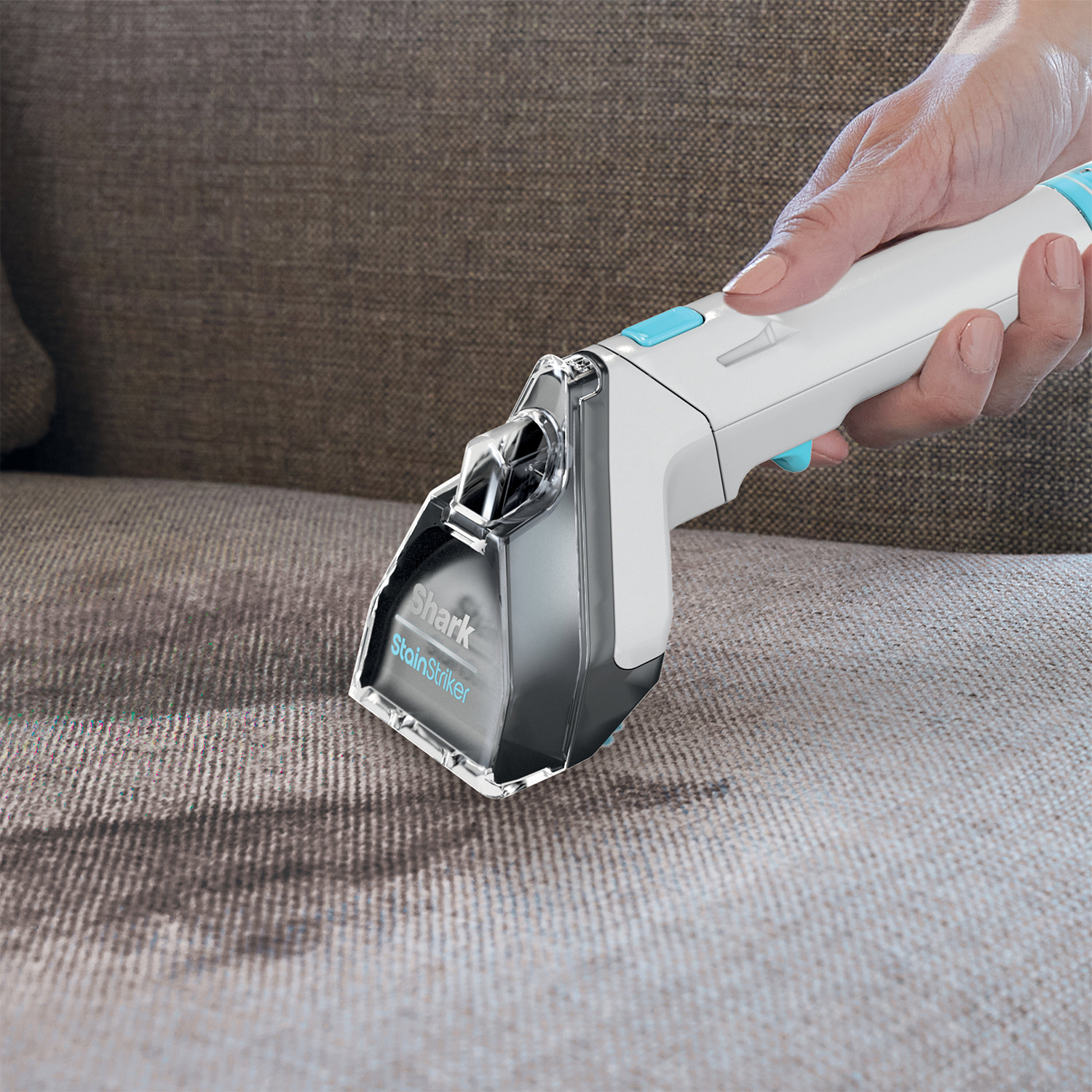 Mano con uno Shark StainStriker bianco che pulisce un divano. Il pulitore è bianco e blu.