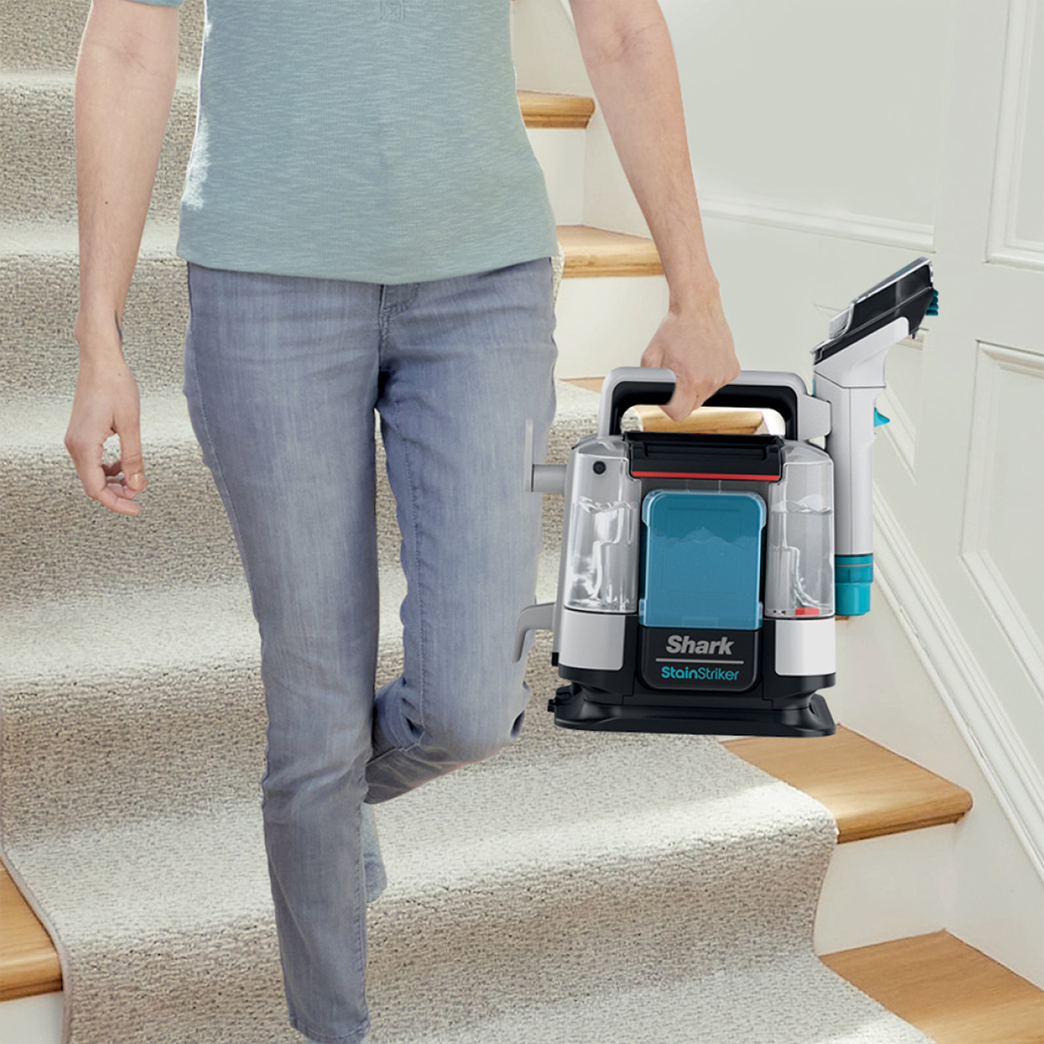Una persona che trasporta un pulitore Shark StainStriker su scale rivestite di moquette.