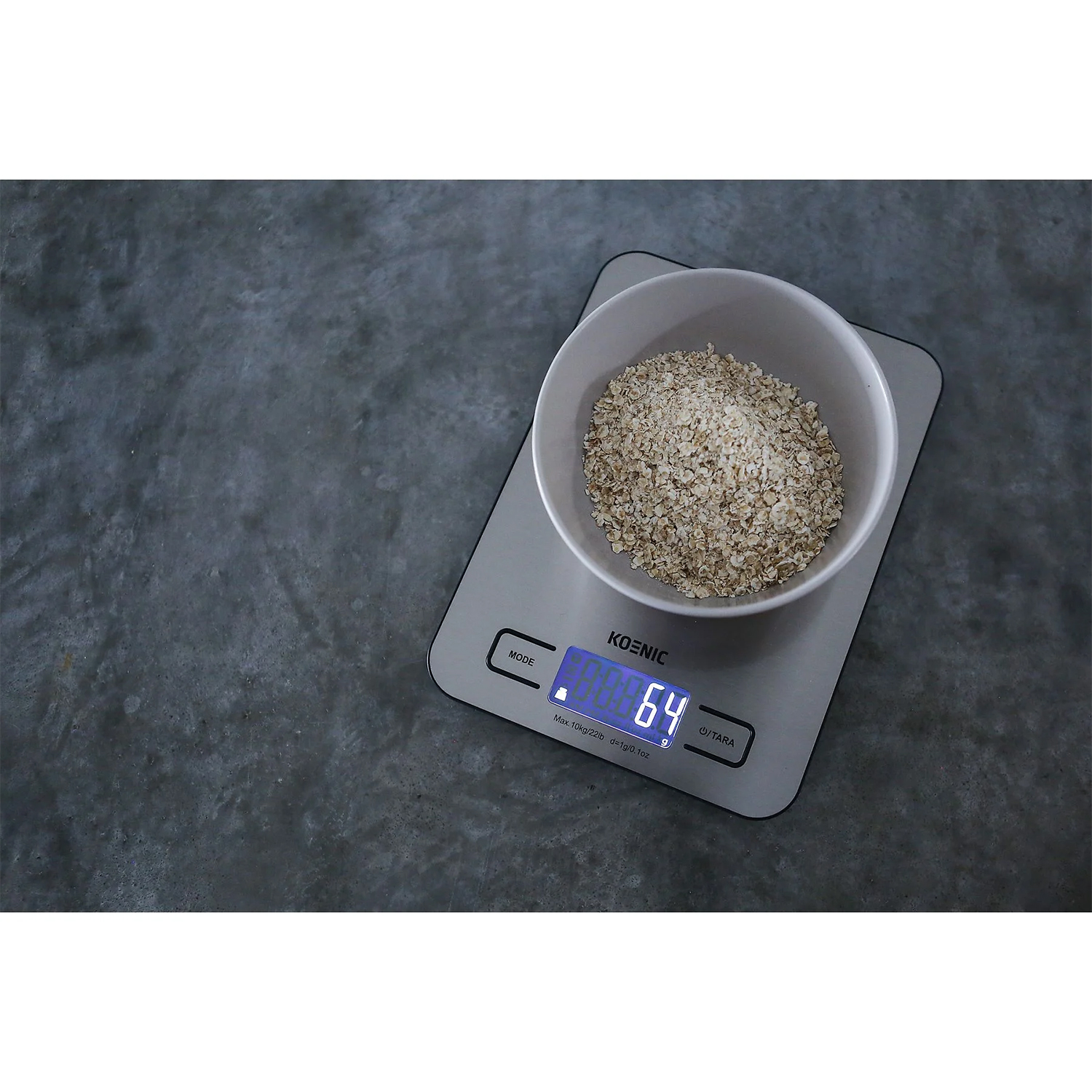 Bilancia da cucina digitale con farina d'avena in una ciotola, che mostra un peso di 64 sullo schermo.