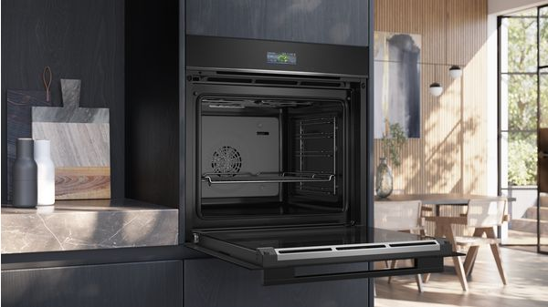 Un horno negro abierto con puerta de vidrio, mostrando el interior.