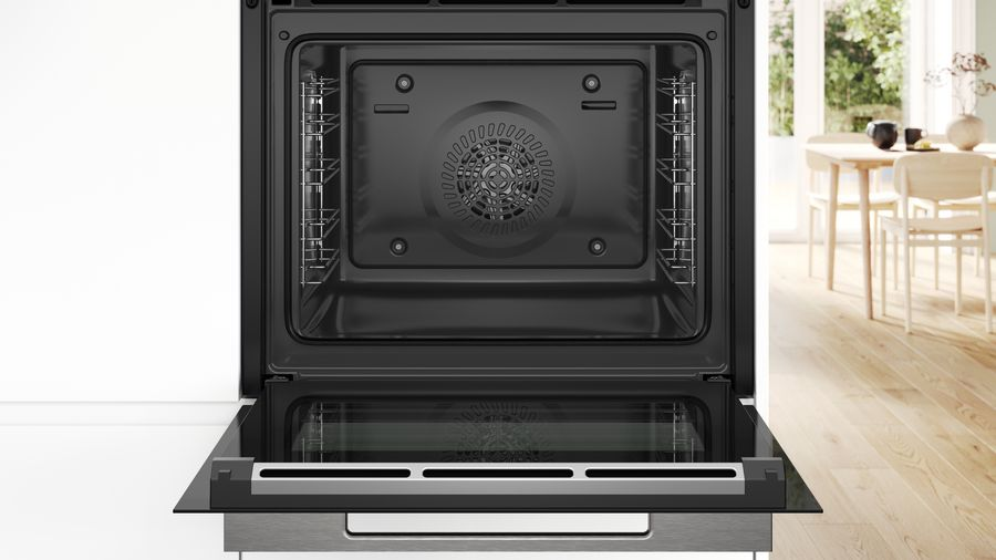Interior de horno negro abierto con la puerta abierta. El interior tiene un ventilador y rejillas metálicas.