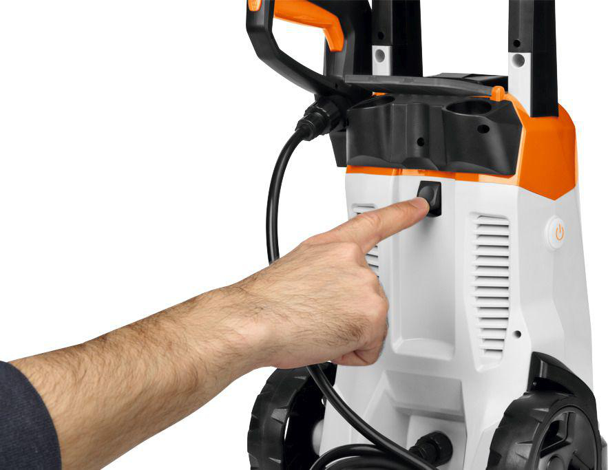Hand drückt einen Einschaltknopf an einem weiß-orangenen Hochdruckreiniger.