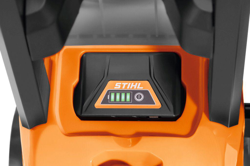 Nahaufnahme eines orange-schwarzen STIHL-Akkuladegeräts mit grünem Akkuladestand.