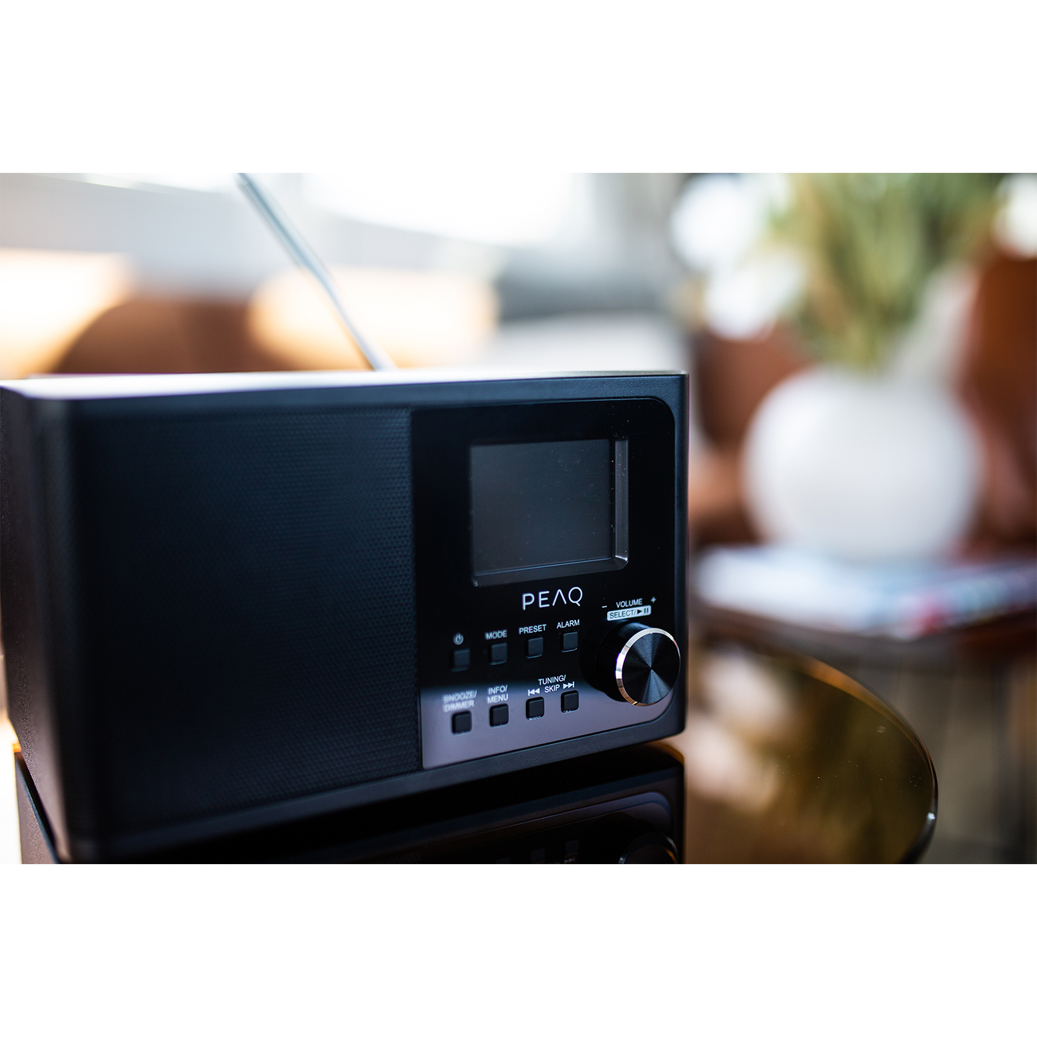 Radio PEAQ nera su un tavolo con superficie nera. Lo schermo è acceso.