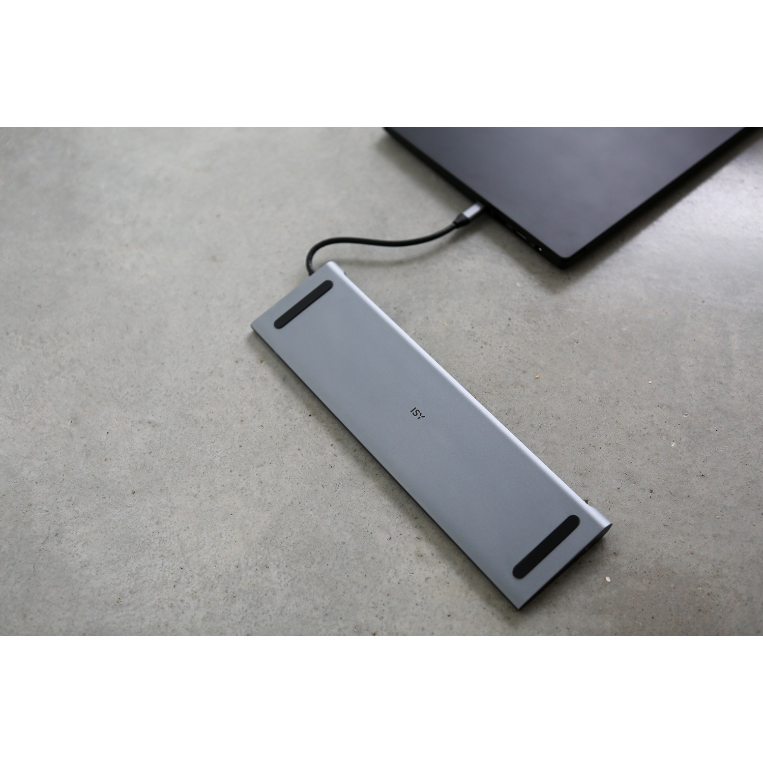 Un hub argentato si collega a un laptop nero su una superficie grigia.