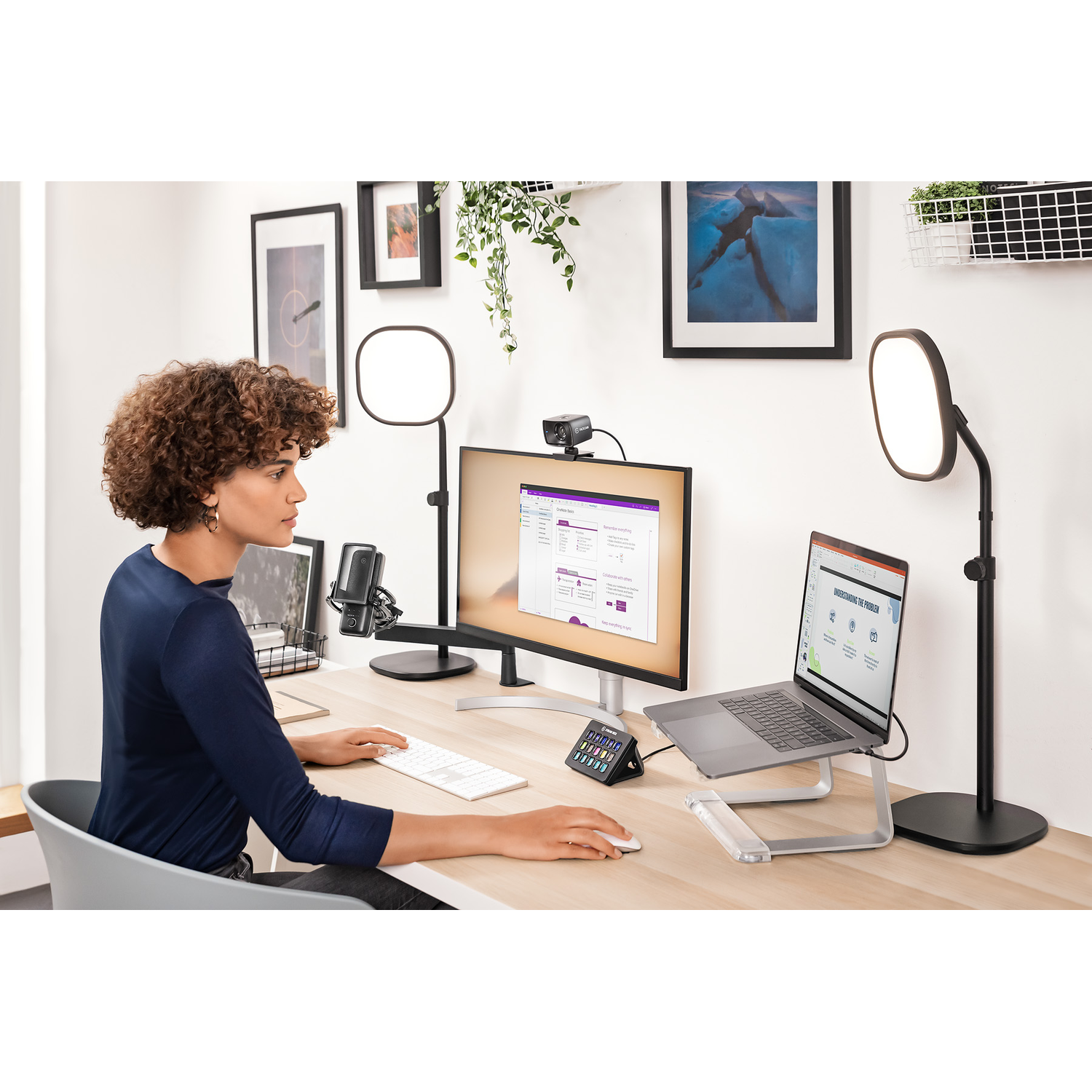 Vrouw die werkt aan een bureau met monitor, laptop, webcam en lampen. Moderne kantooromgeving.