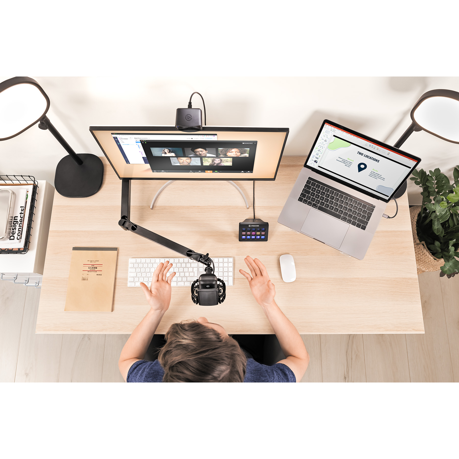 Een man zit aan een bureau met een laptop, microfoon en andere apparatuur.