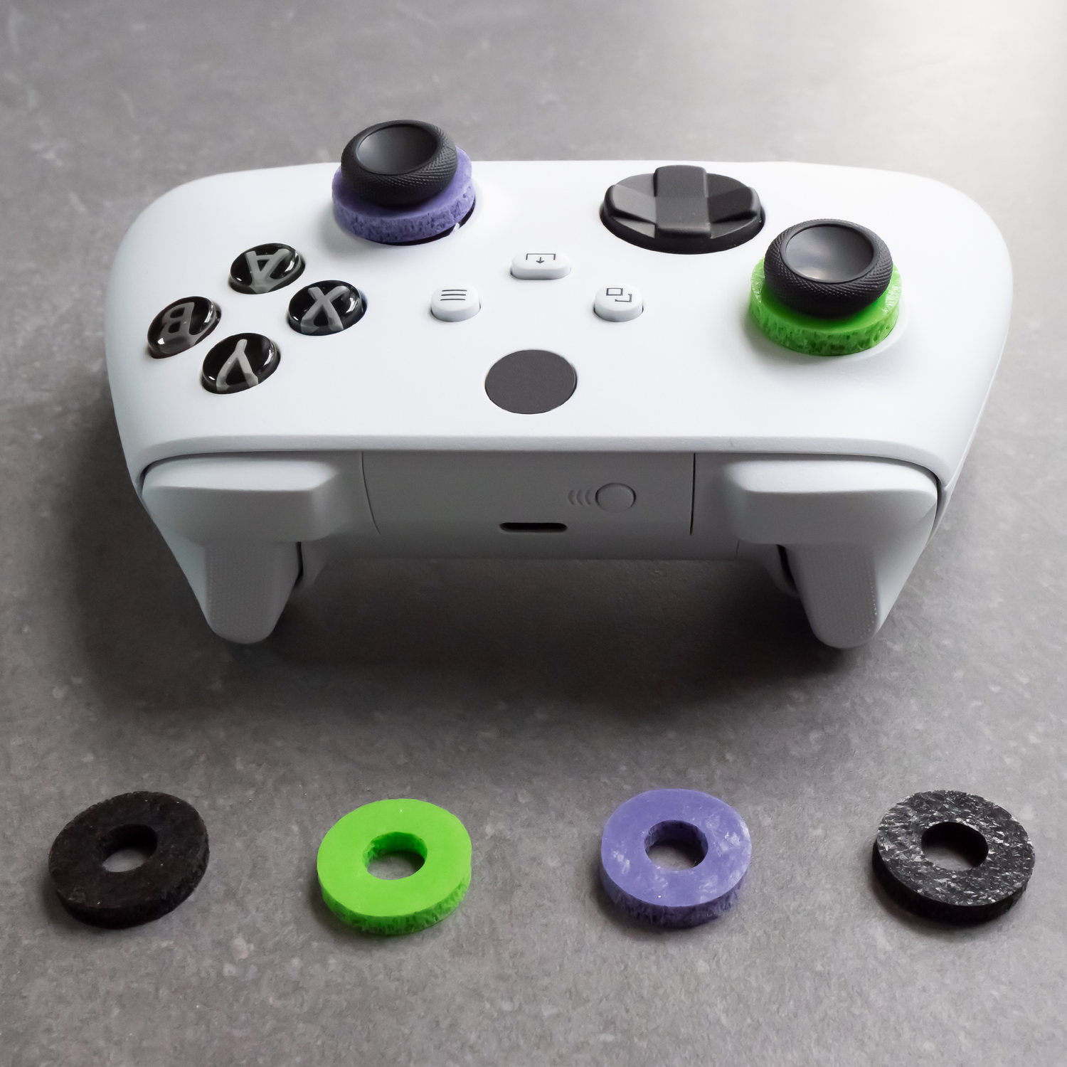White game controller with black buttons and colorful, textured joystick covers.
