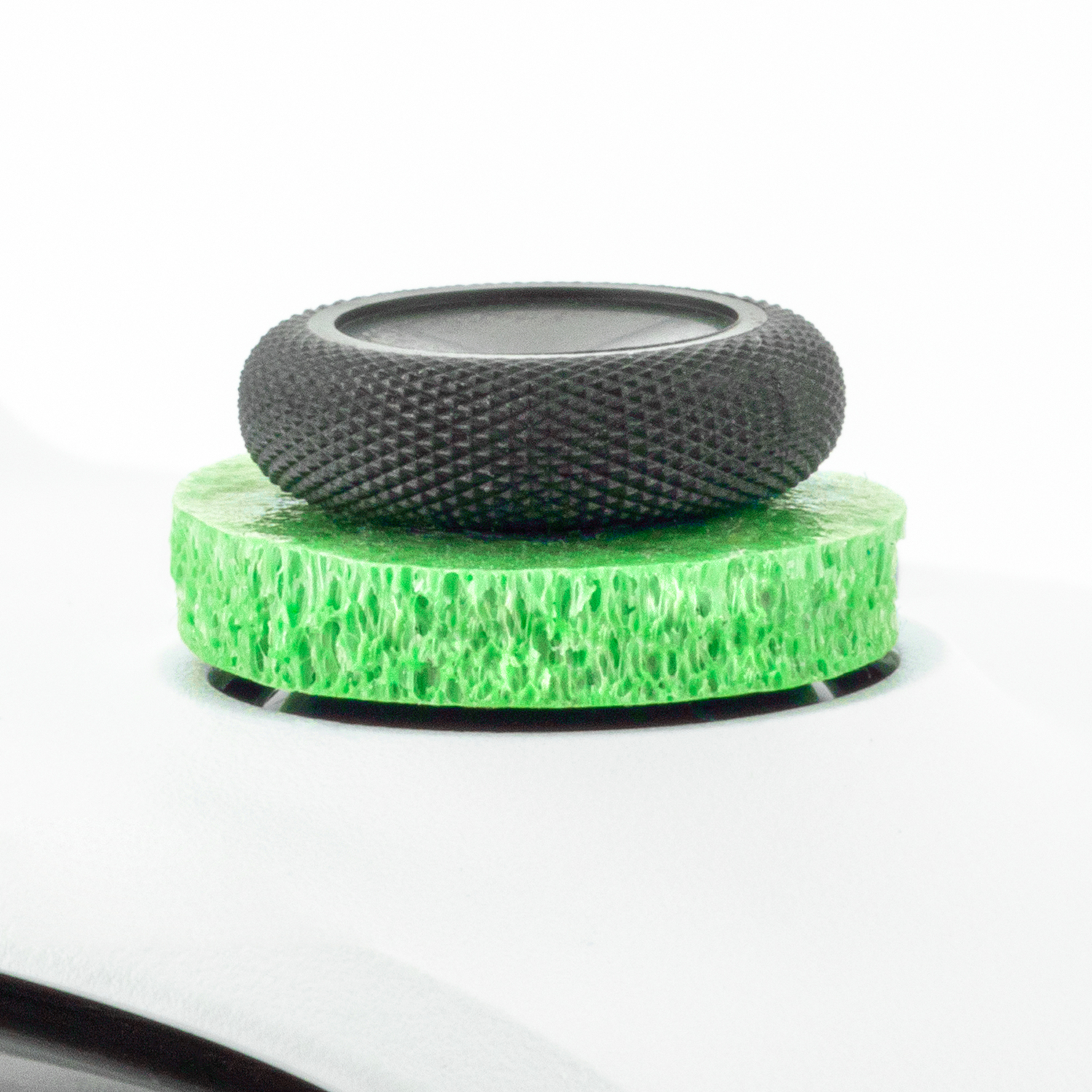 Two-tiered sculpture: black textured top, green textured base. White background.