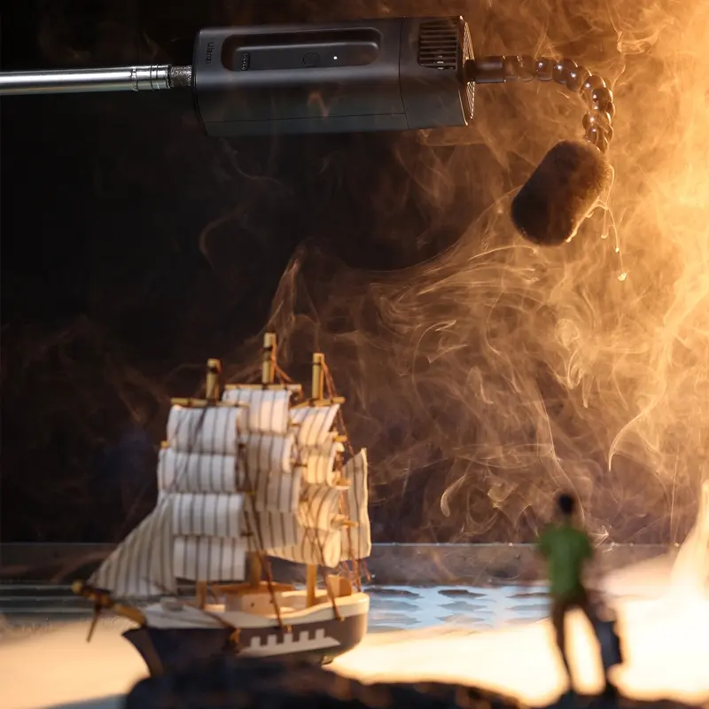 Miniatűr hajó vízben, füst, fény. Fekete kar mikrofonnal. Sötét, elmosódott háttér.
