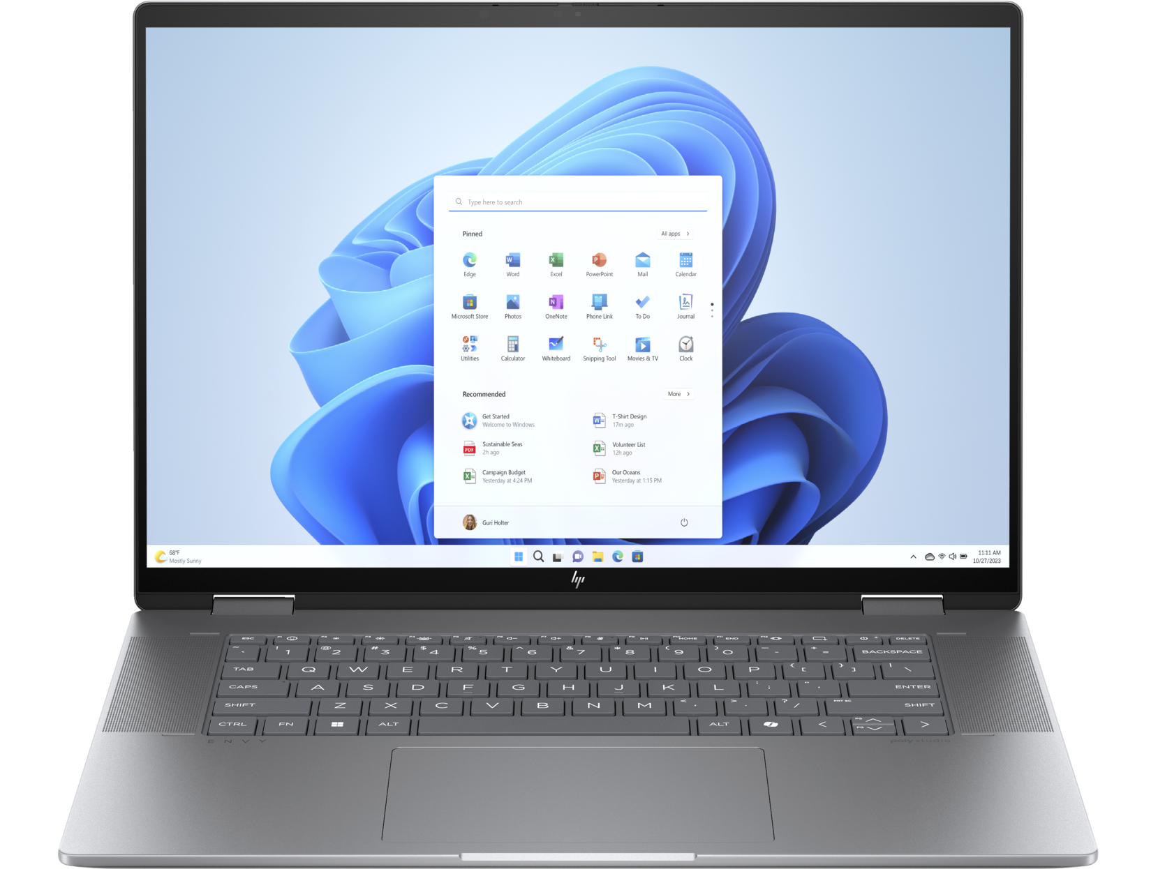 Un portátil plateado en un escritorio, la pantalla muestra una interfaz de Windows 11.