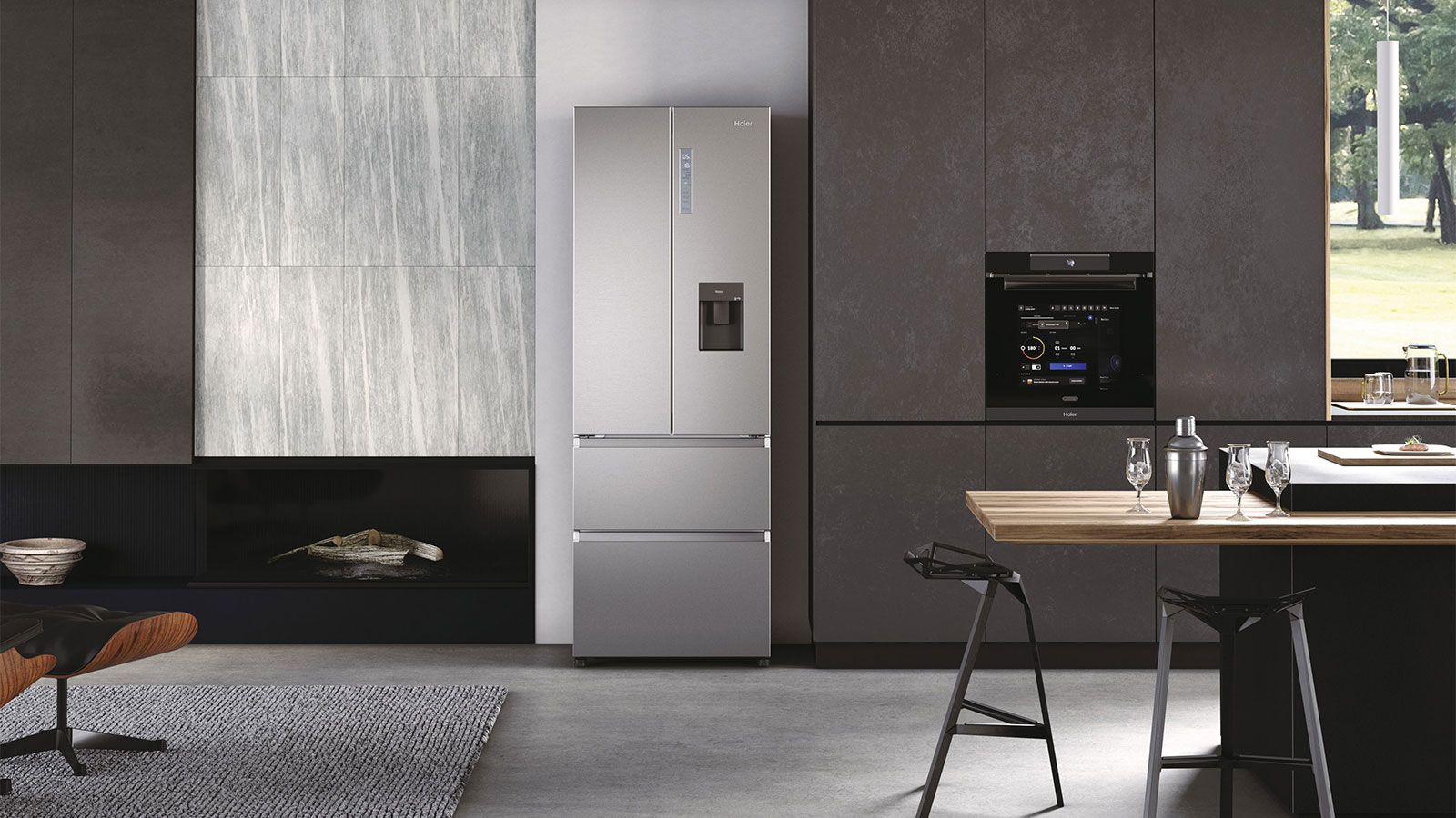 Eine moderne Küche mit großem silbernen Kühlschrank, Backofen, Holzbar und Kamin. Der Raum ist gut beleuchtet.