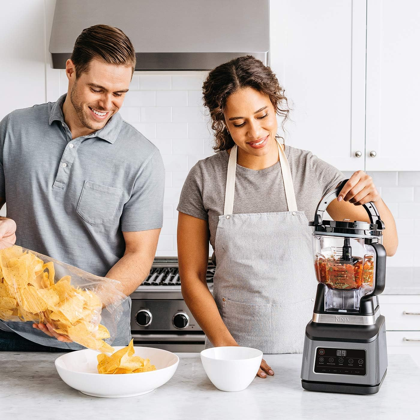 Deux personnes préparent de la nourriture. L'un verse des frites, l'autre utilise un mixeur. Cuisine.