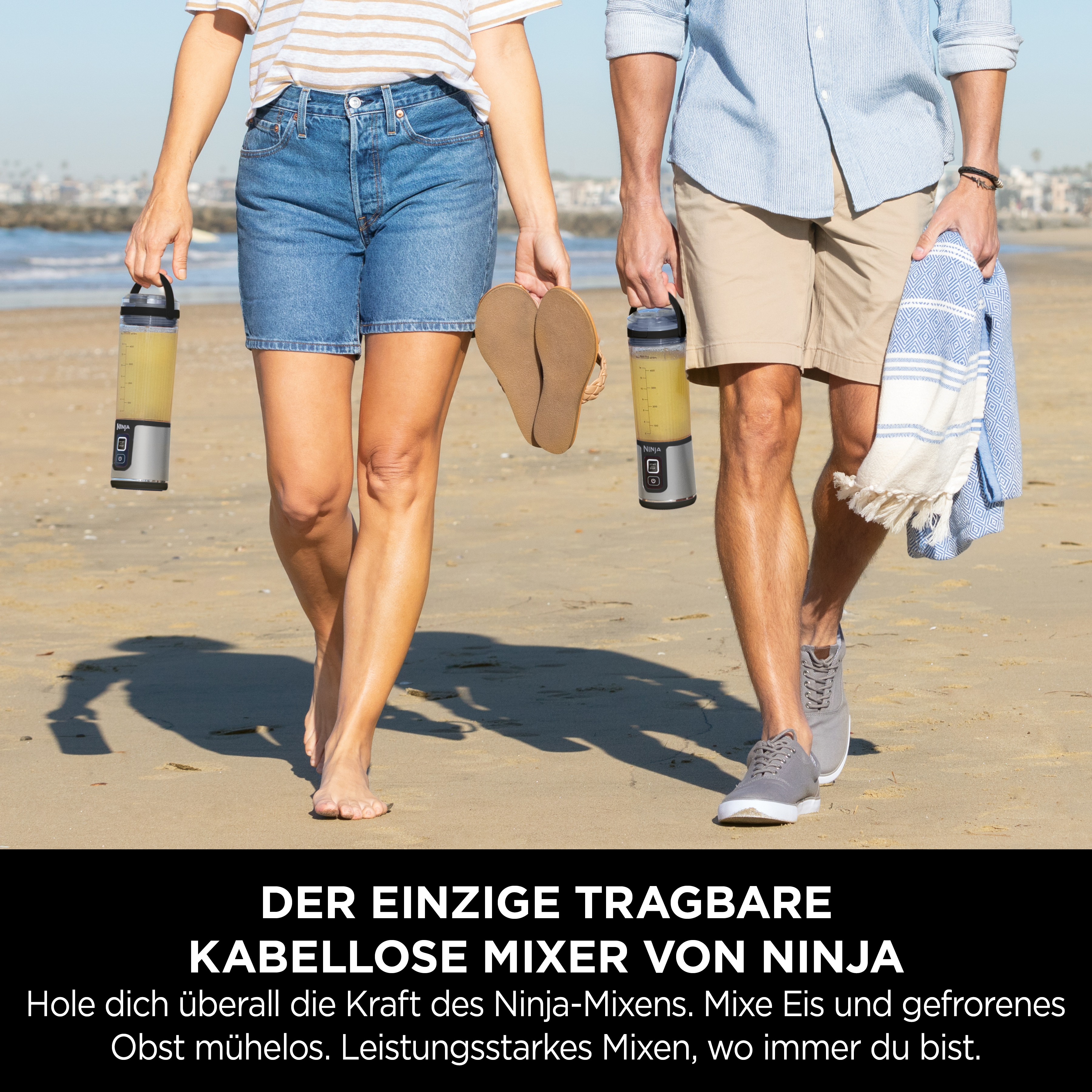 Zwei Personen gehen am Strand, jede hält einen Mixer. Text: Der einzige tragbare Ninja-Mixer.