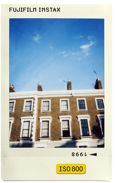 Fujifilm Instax fotó egy épület homlokzatáról kék ég alatt. Sárga ISO 800 felirat alul.