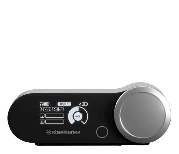 Czarny i srebrny interfejs audio z pokrętłem głośności i ekranem. Marka to SteelSeries.