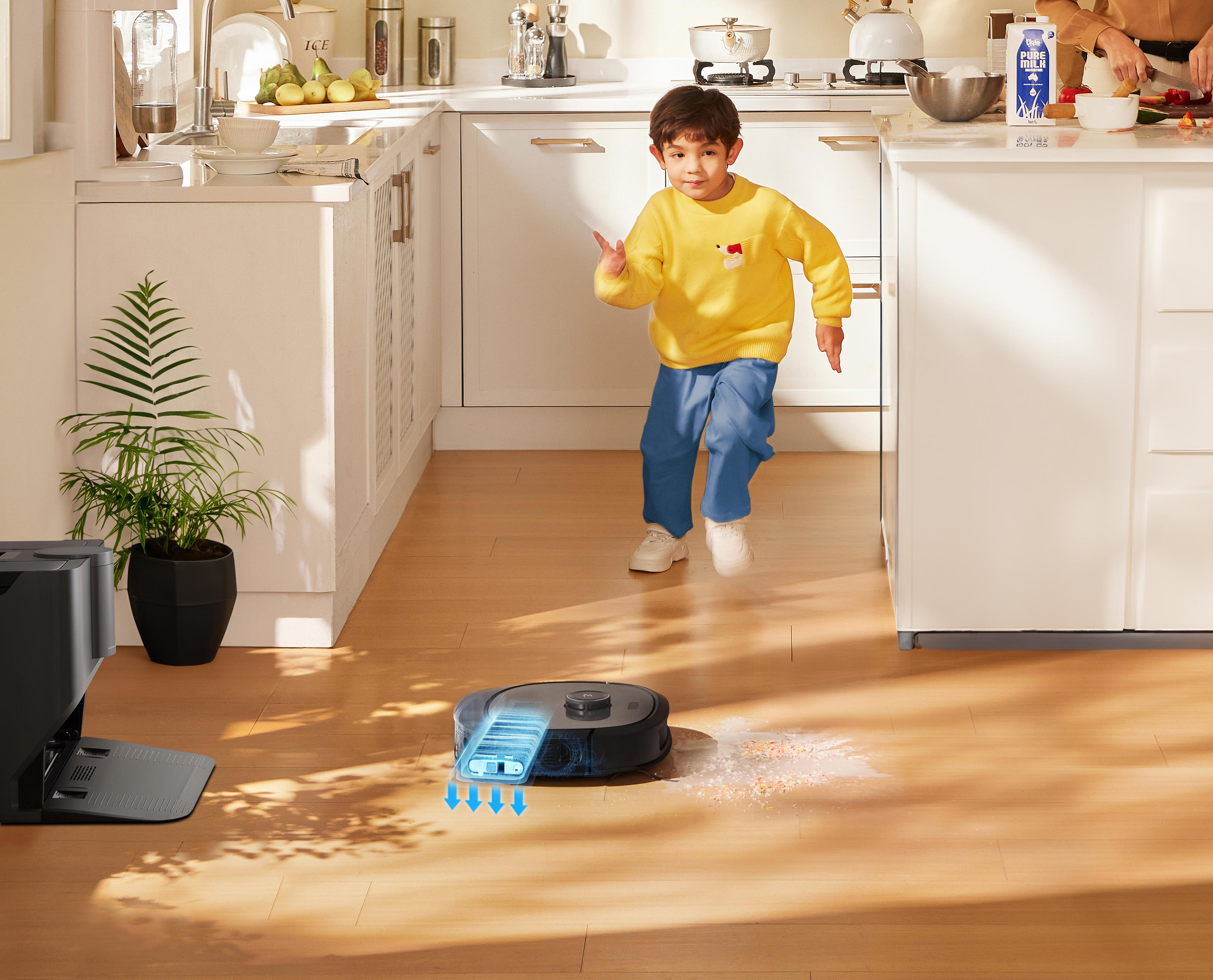 Ein Kind, das in einer Küche rennt, während ein Roboter-Staubsauger den Boden reinigt.