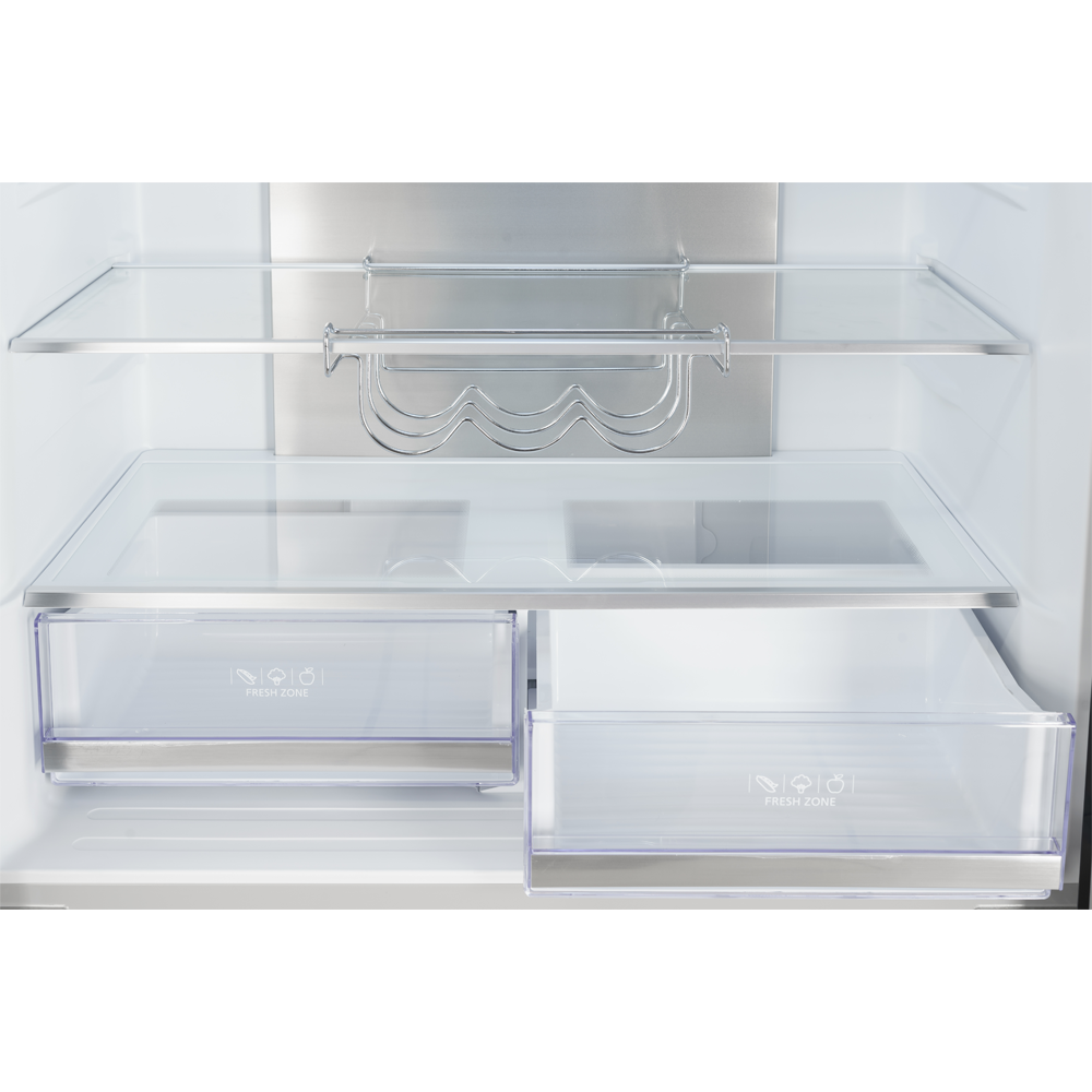Dentro de un refrigerador: estantes de vidrio, cajones transparentes etiquetados como 'Fresh Zone', un botellero de metal y una parte trasera de acero inoxidable.