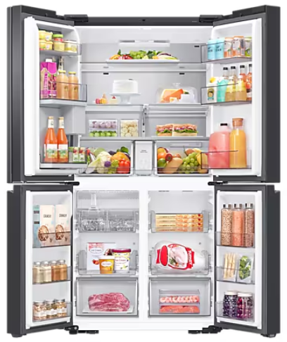 Otwarta lodówka wypełniona artykułami spożywczymi. Widoczne owoce, warzywa, napoje i pakowane produkty spożywcze w różnych przegródkach.