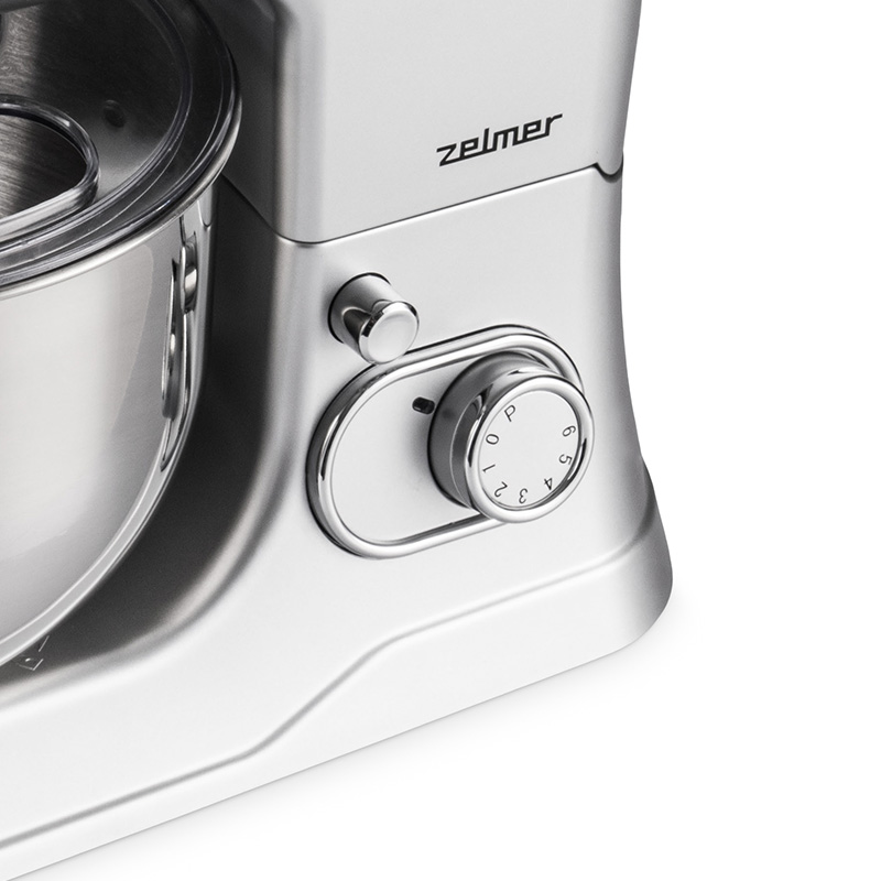 Srebrny mikser kuchenny z pokrętłem prędkości i logo Zelmer, zbliżenie na białym tle.