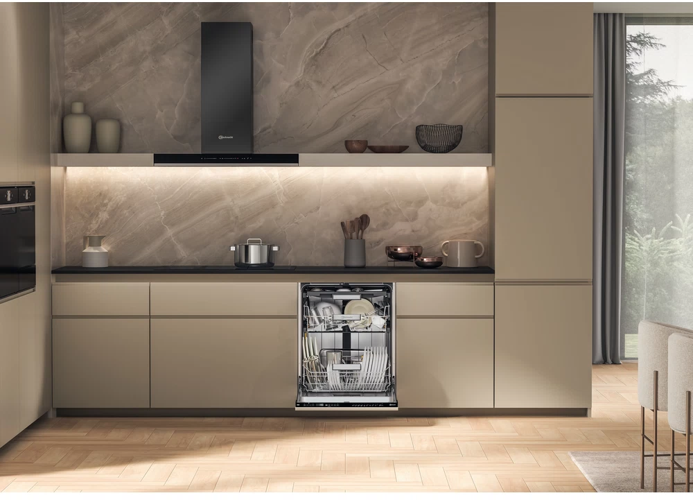 Cucina con lavastoviglie aperta. Mobili beige, piano nero e cappa aspirante.