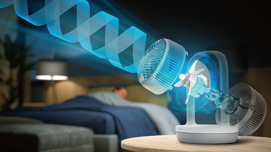 Ventilátor kék légáramlással egy ágy fölött, amelyben egy személy alszik, és egy lámpa az asztalon.
